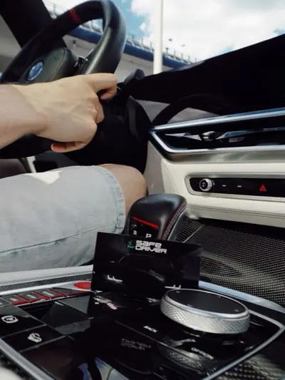 Водій за кермом BMW, на консолі візитівка Safe Driver